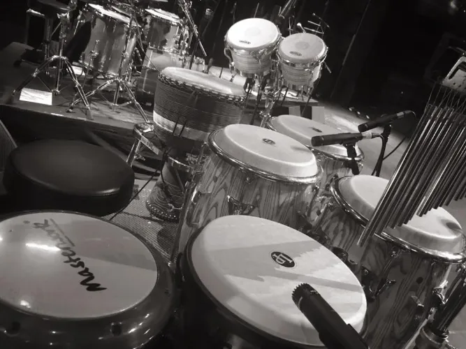 Latin Percussion setup with congas, bongos, djembe wind chimes with a drum kit in the backgroud
